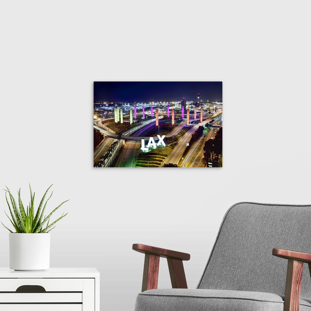 A modern room featuring West coast aero port lit up at night by glowing towers and traffic flowing through the roads whic...