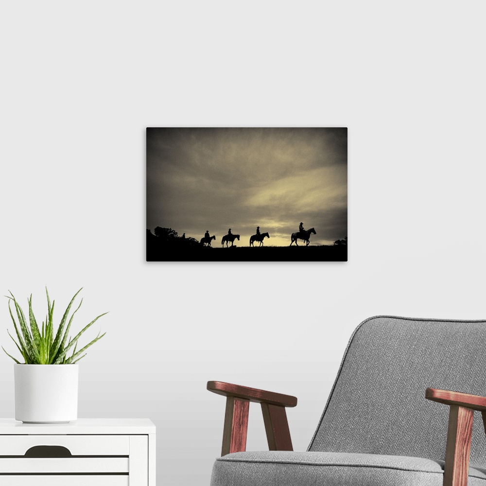 A modern room featuring Sepia-toned photo of four cowboys on horseback silhouetted against an overcast sky.