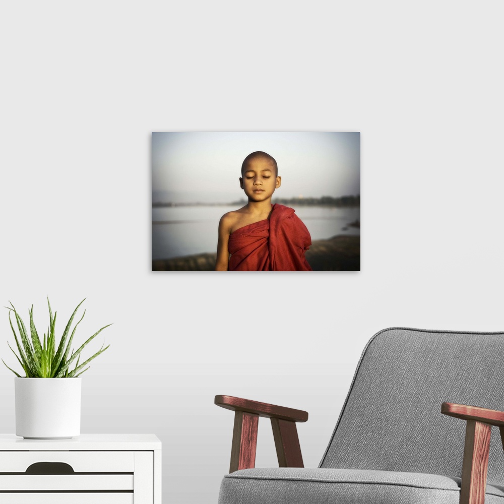 A modern room featuring Young Burmese monk by the water, Mandalay, Burma