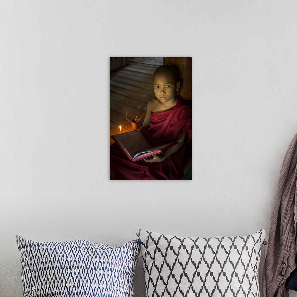 A bohemian room featuring Young Burmese monk reading by candlelight