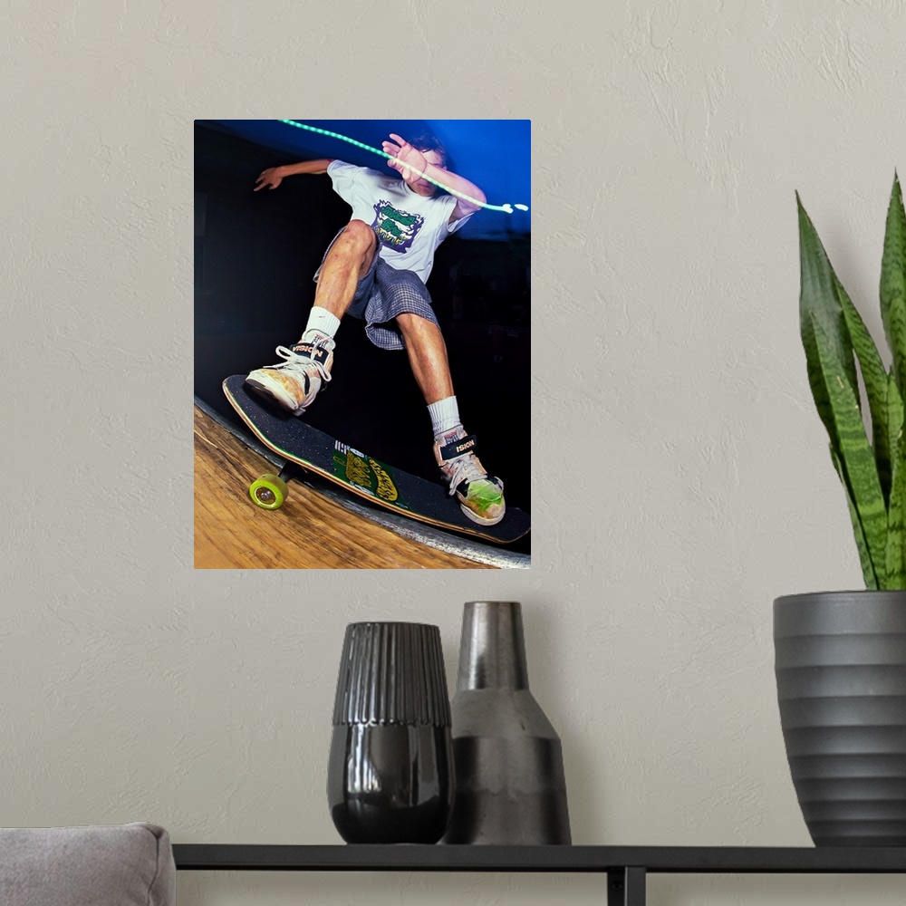 A modern room featuring Danny Sargent doing a kick flip on his skateboard at night in San Francisco, 1989.