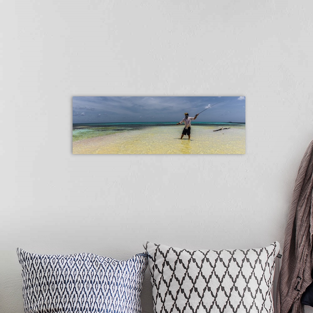 A bohemian room featuring A man fly fishing in the ocean on a tropical beach in Belize, 2016.
