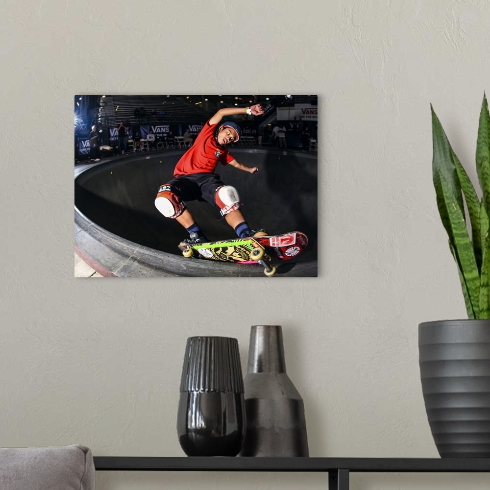 A modern room featuring Kiko Saucee grinding his skateboard on a railing at Vans Off The Wall Skatepark in Huntington Bea...