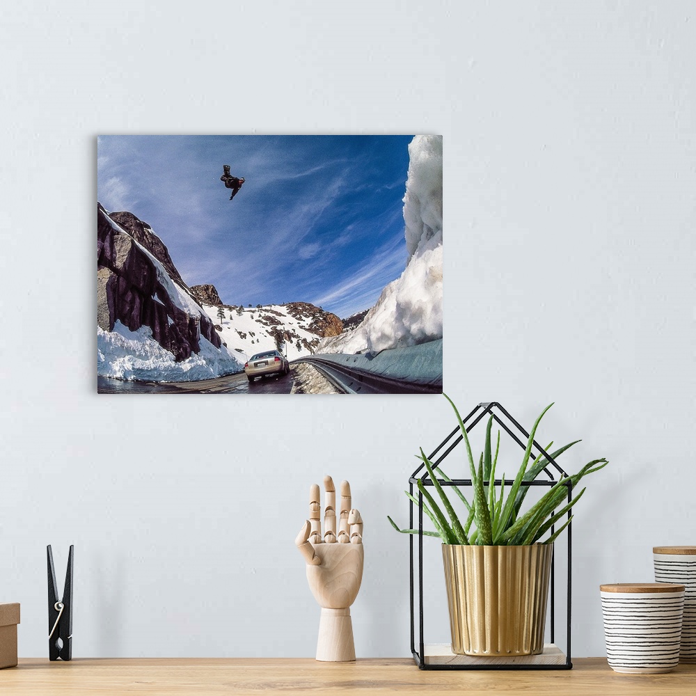 A bohemian room featuring Nate Mott flying on his snowboard over the Donner Summit, as a car passes by below, California, m...