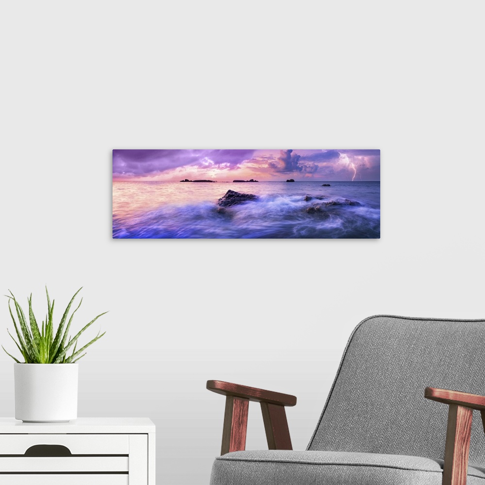 A modern room featuring Colorful calm sea during sunset. A storm is approaching over the horizon. Colorful dark clouds in...