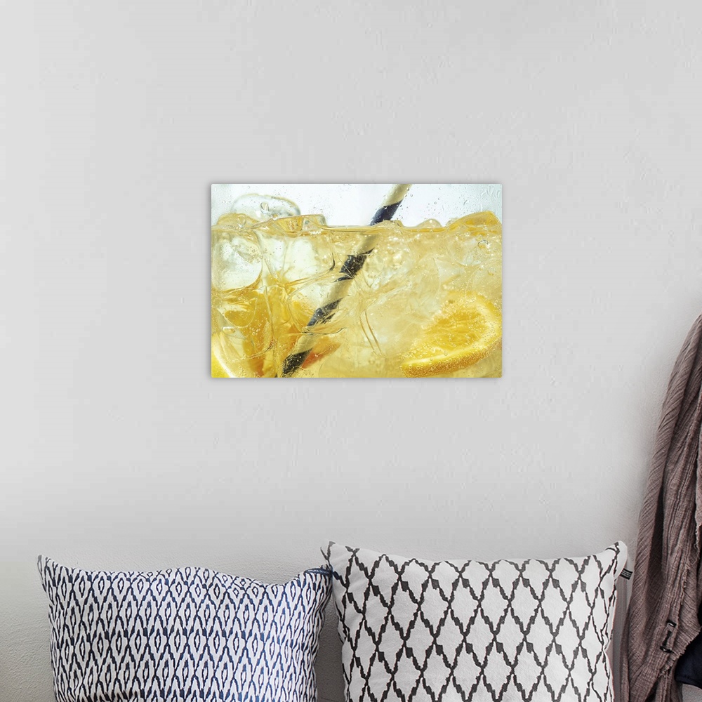 A bohemian room featuring Close up of lemon slices in stirring the lemonade and ice cubes on background. Texture of cooling...