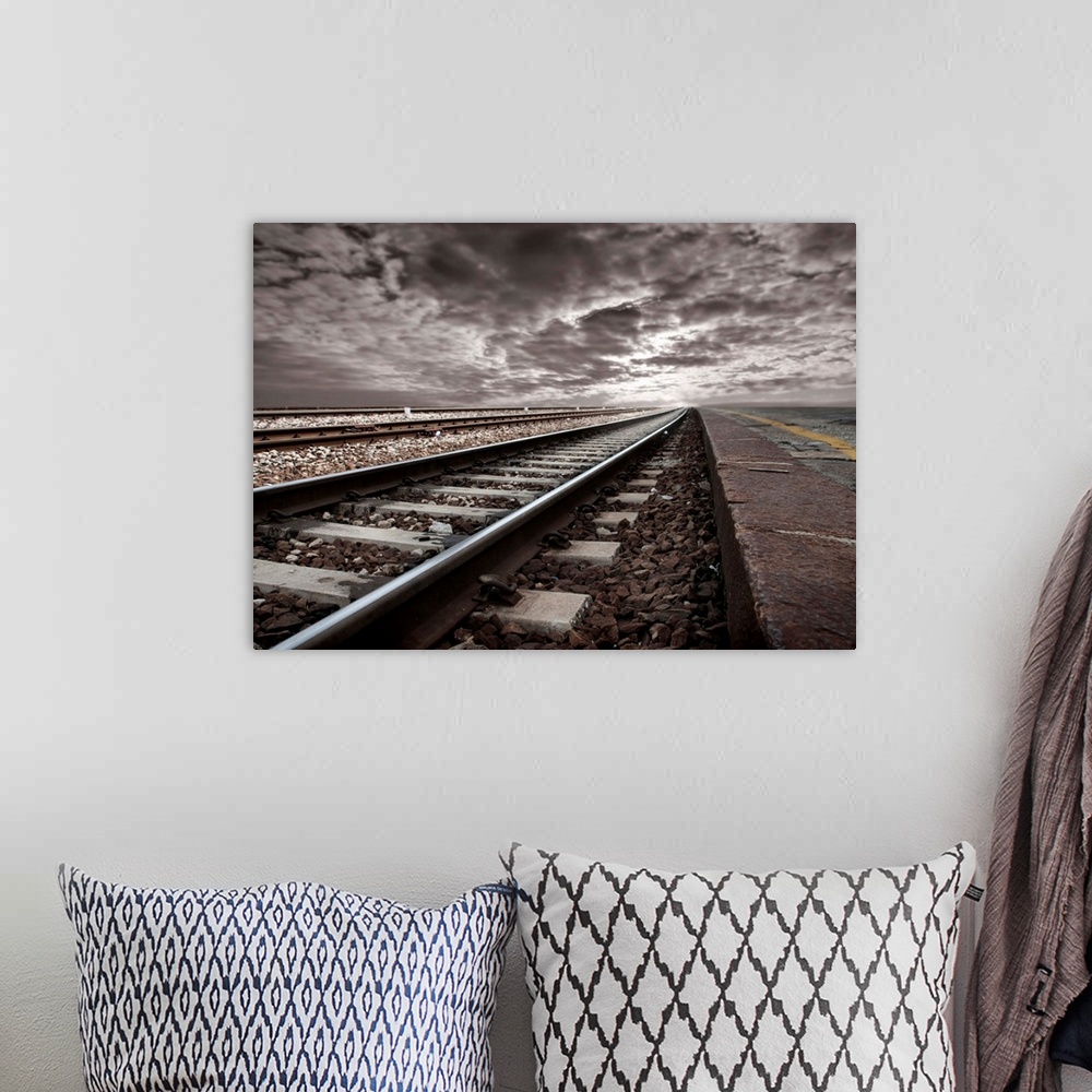 A bohemian room featuring empty railway tracks in a stormy landscape