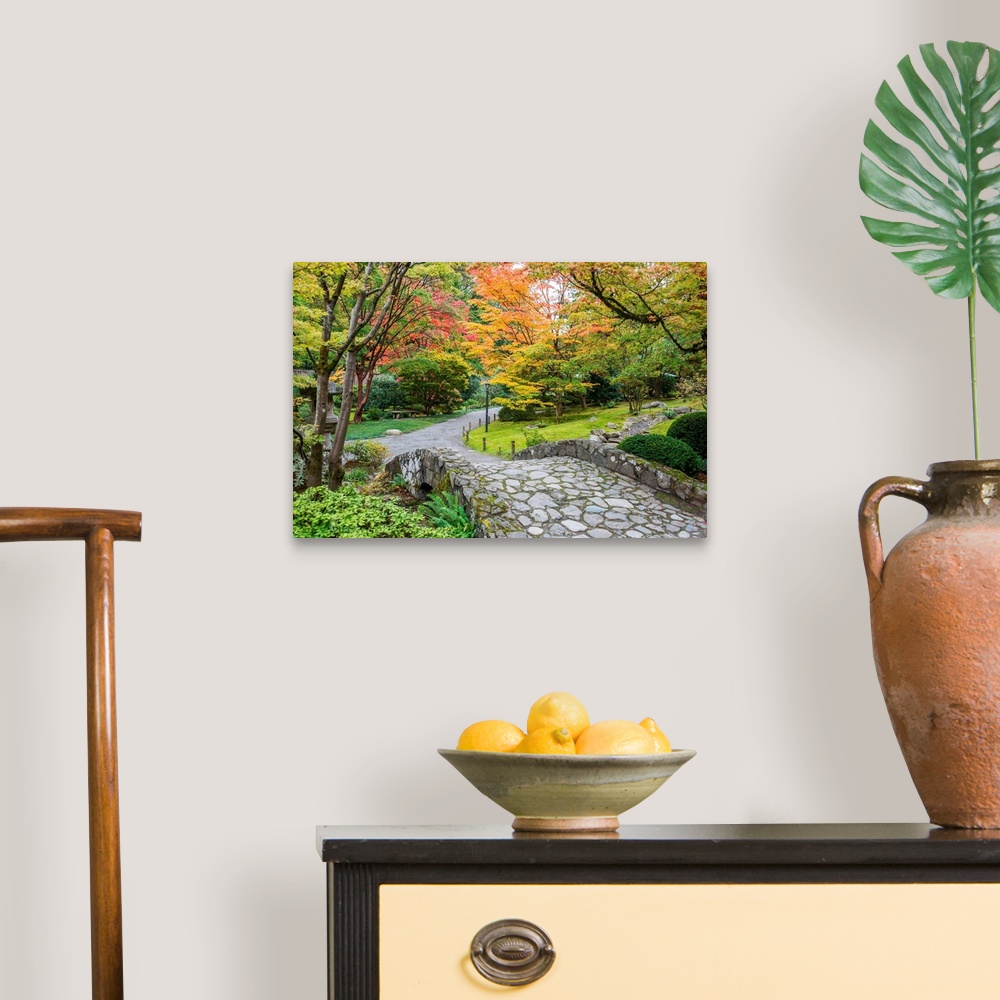 A traditional room featuring Autumn colors along a winding walking path and stone bridge in a Japanese garden.