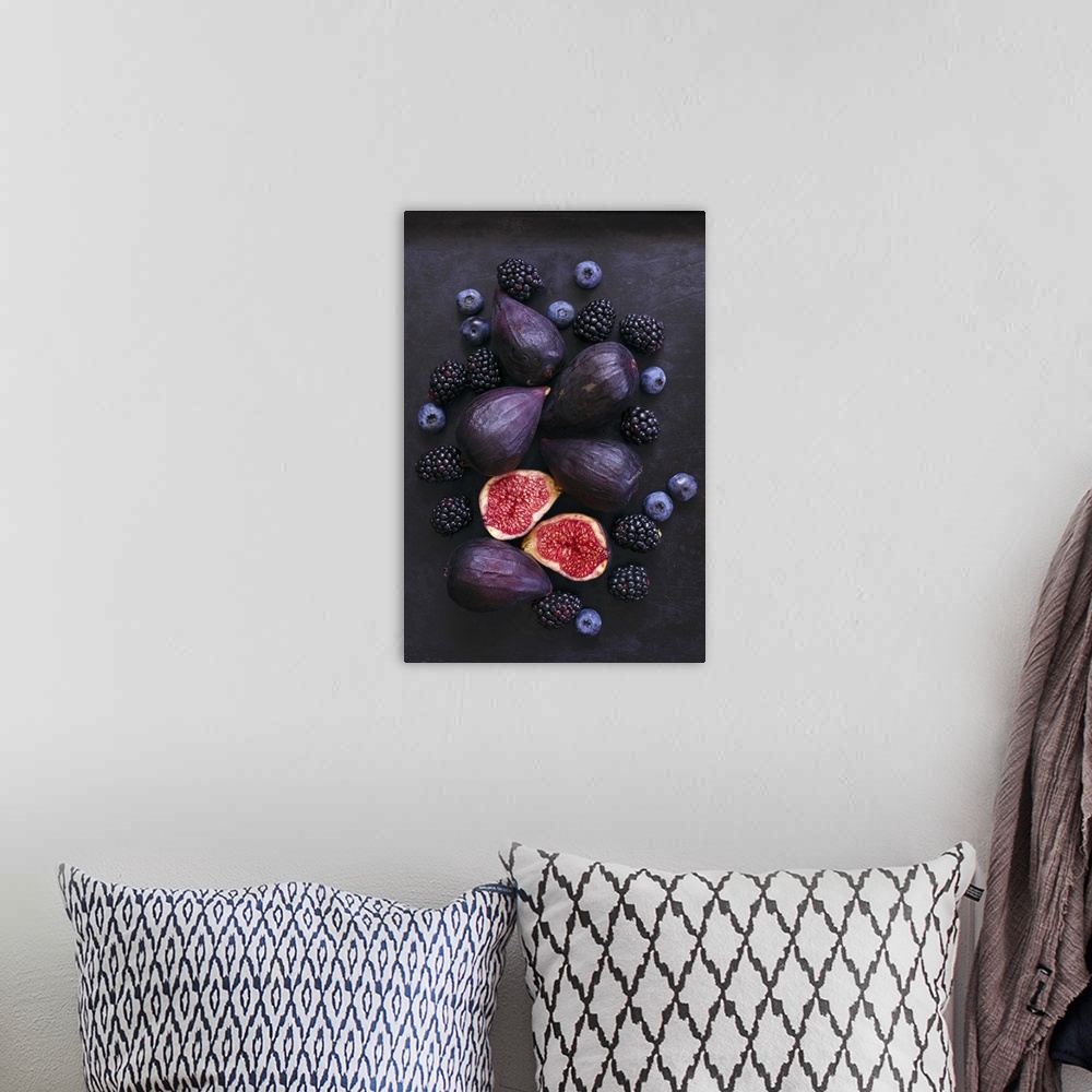 A bohemian room featuring Ripe, purple whole and cut figs, blackberries, and blueberries on black background.