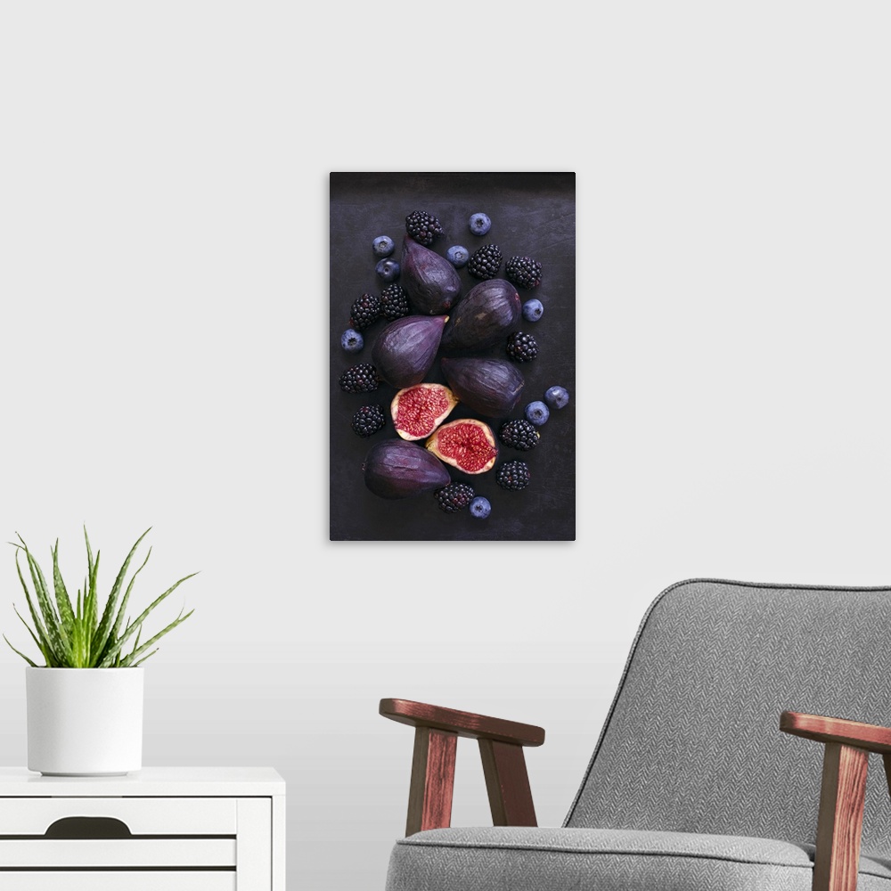 A modern room featuring Ripe, purple whole and cut figs, blackberries, and blueberries on black background.
