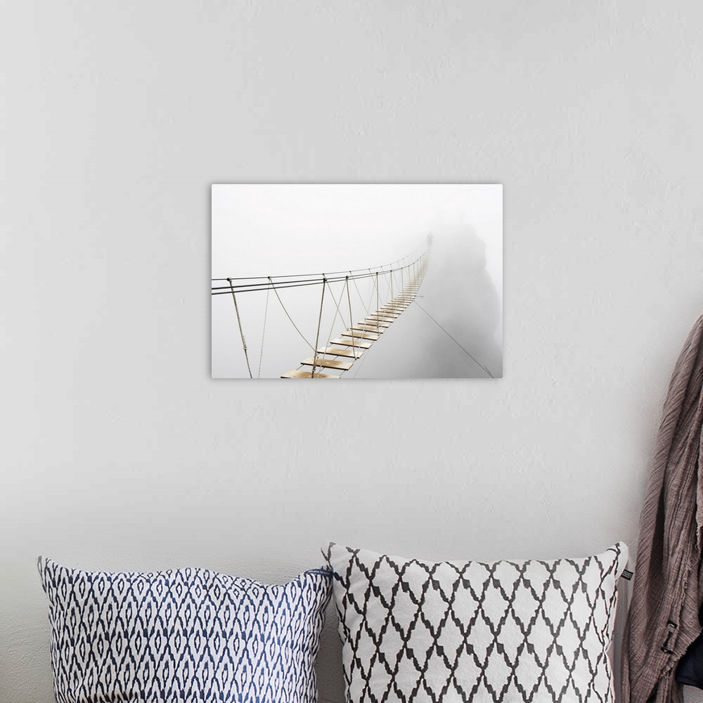 A bohemian room featuring Fuzzy man walking on hanging bridge vanishing in fog. Focus is on the middle of bridge.