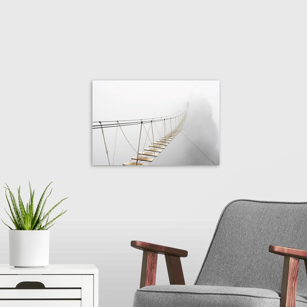 A modern room featuring Fuzzy man walking on hanging bridge vanishing in fog. Focus is on the middle of bridge.