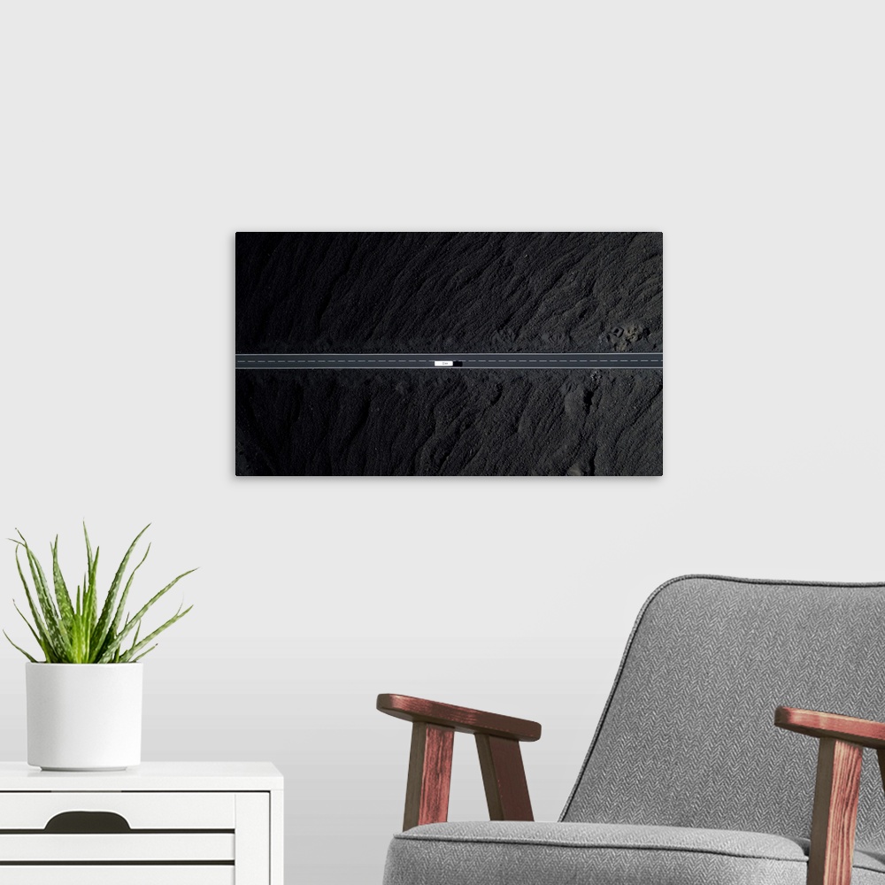 A modern room featuring Road With White Car Surrounded By Black Volcanic Lava