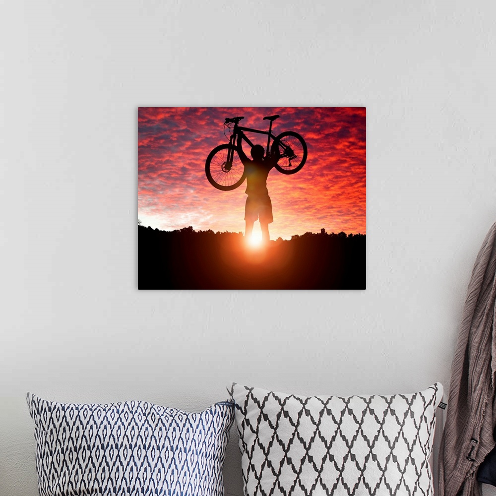 A bohemian room featuring Silhouette Of a mountain biker holding up bike against a sunset sky