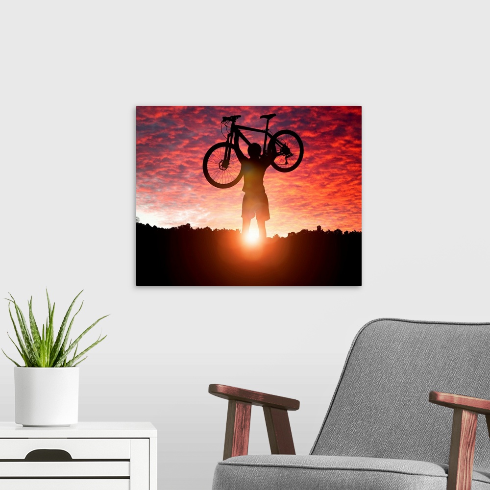 A modern room featuring Silhouette Of a mountain biker holding up bike against a sunset sky