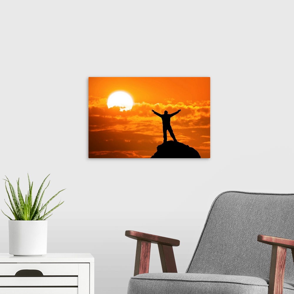 A modern room featuring Silhouette of man on mountain peak with arms outstretched looking at the sun