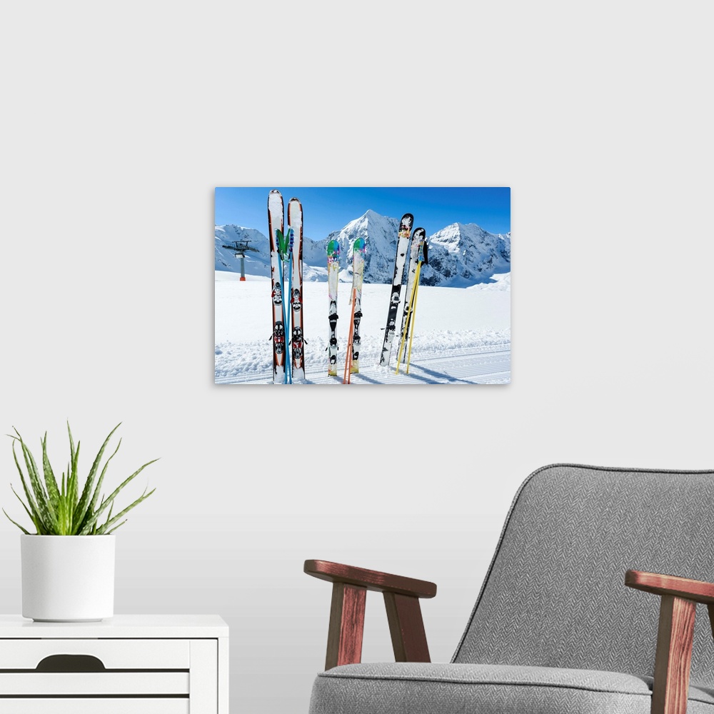 A modern room featuring Skis sticking in the snow on a mountain slope..