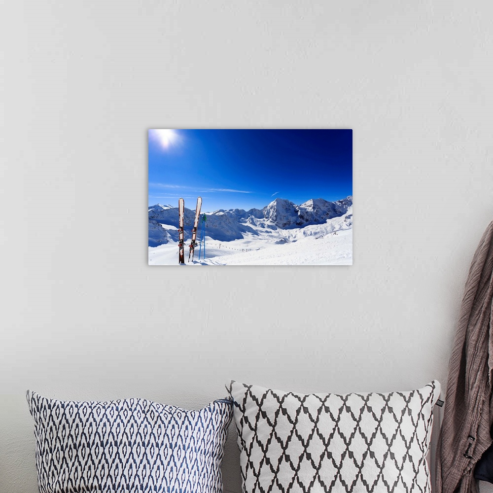 A bohemian room featuring Skis sticking in the snow on a mountain slope.