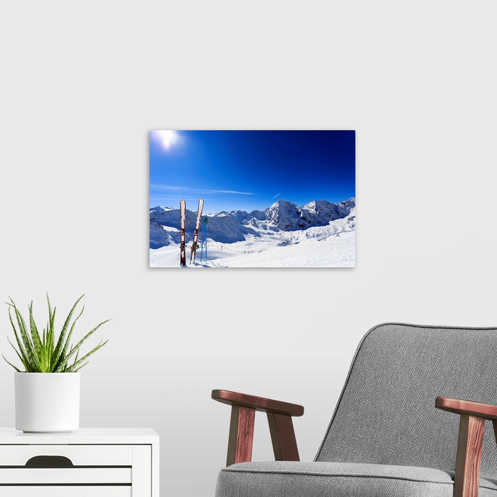 A modern room featuring Skis sticking in the snow on a mountain slope.