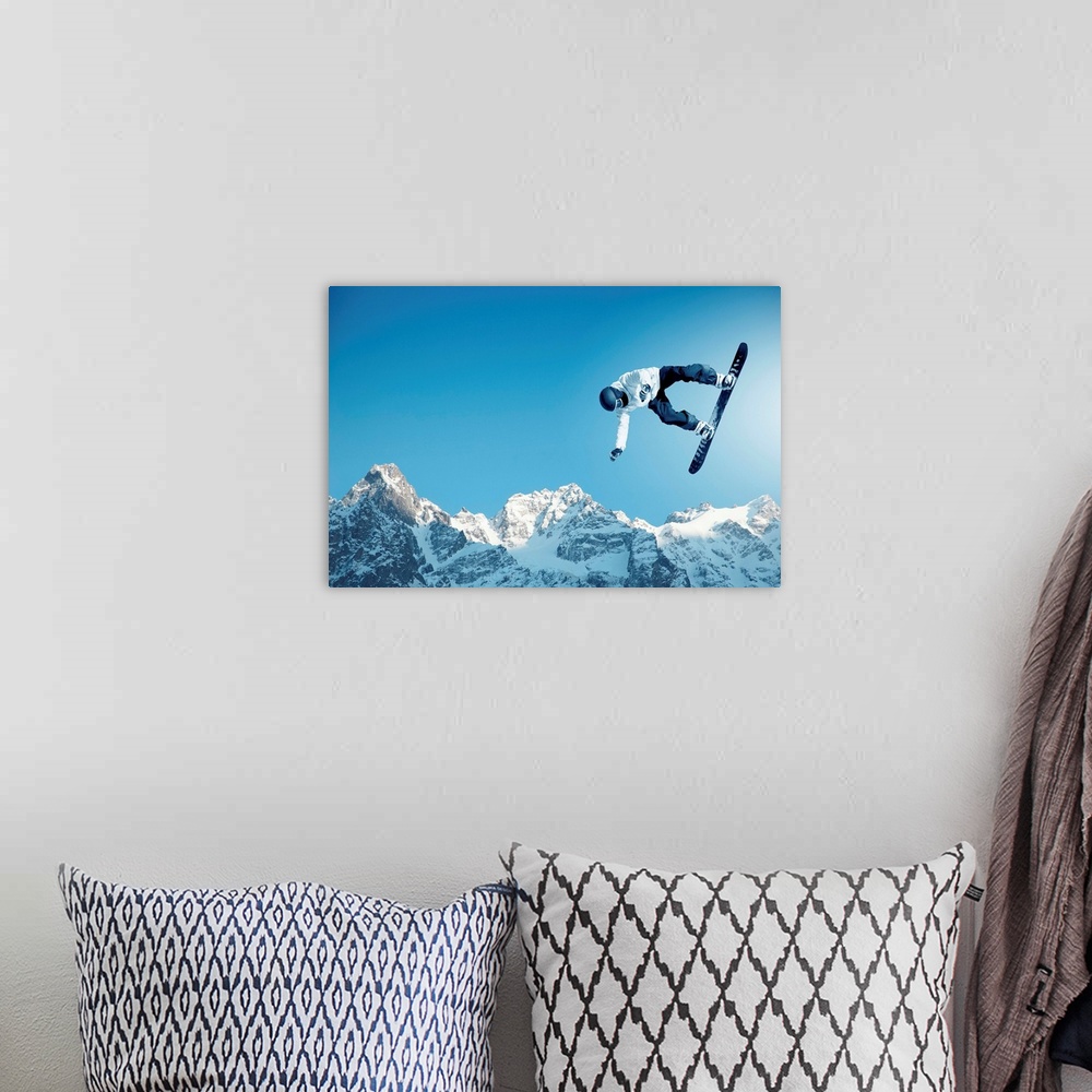 A bohemian room featuring Snowboarder making jump high in clear sky, with mountains in the background.