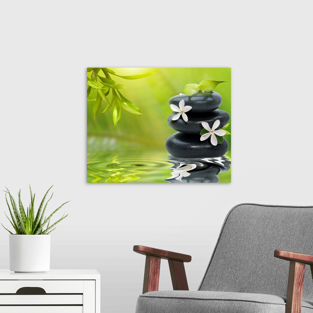 A modern room featuring Spa still life with white flowers on the black stones and bamboo leaves.
