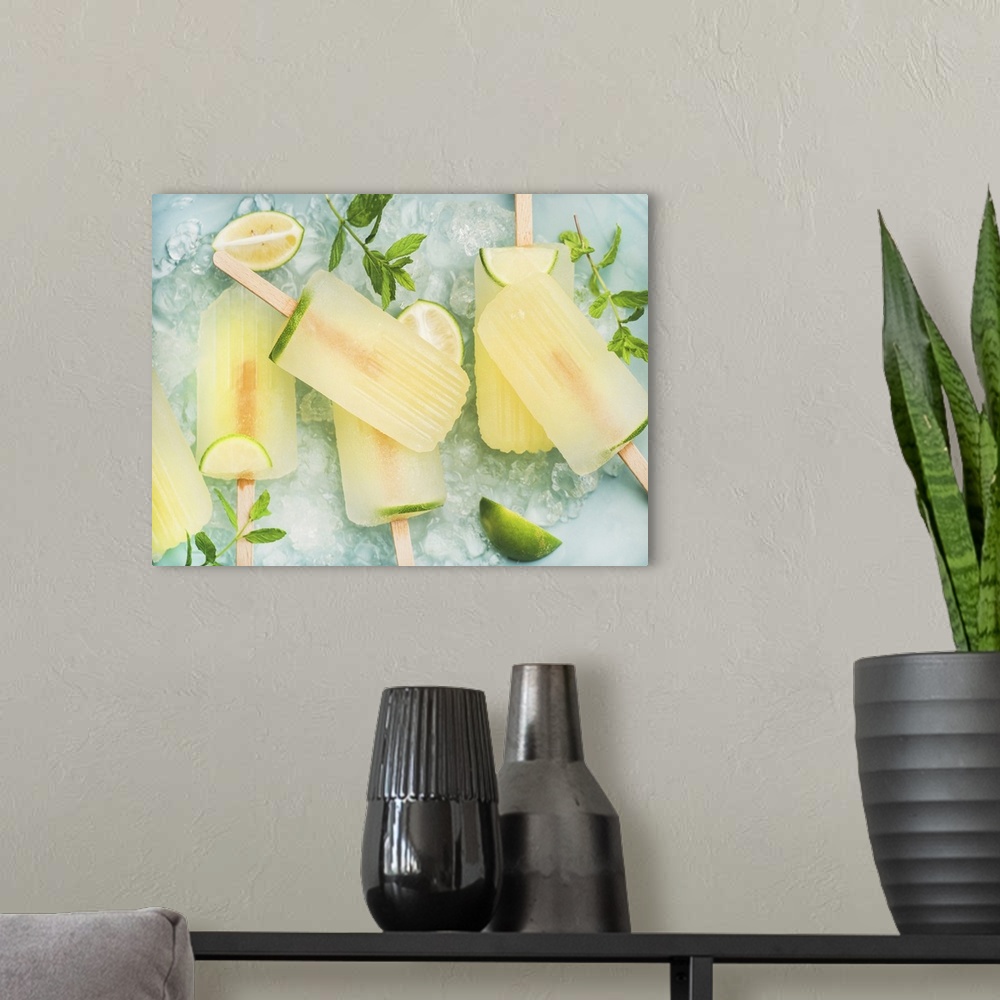 A modern room featuring Summer refreshing lemonade popsicles with lime and mint with chipped ice over blue background, to...