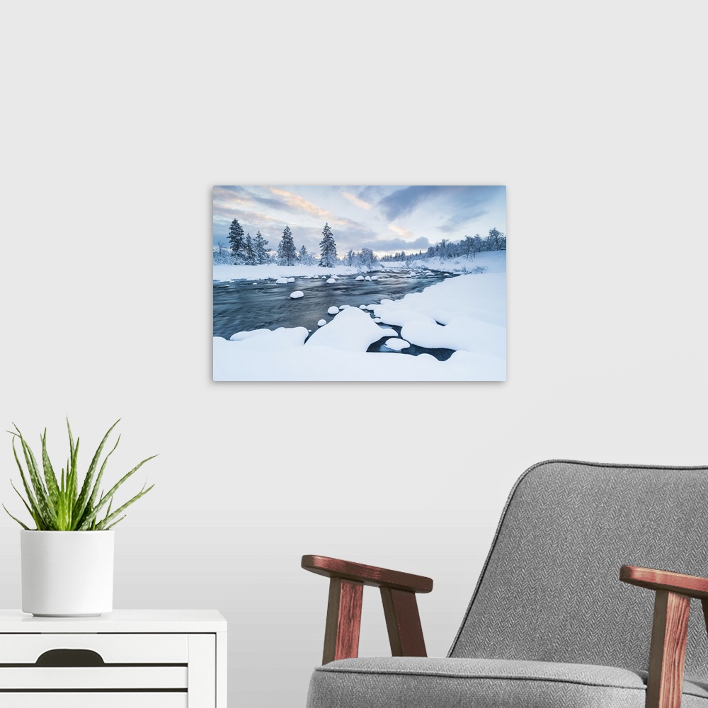 A modern room featuring The river with snow in it and a forest near covered with snow in winter in Sweden.