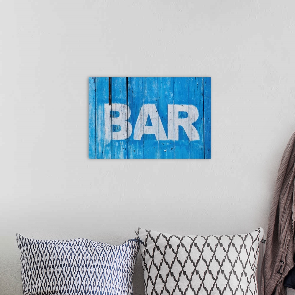 A bohemian room featuring White bar sign painted on a dilapidated blue wooden wall