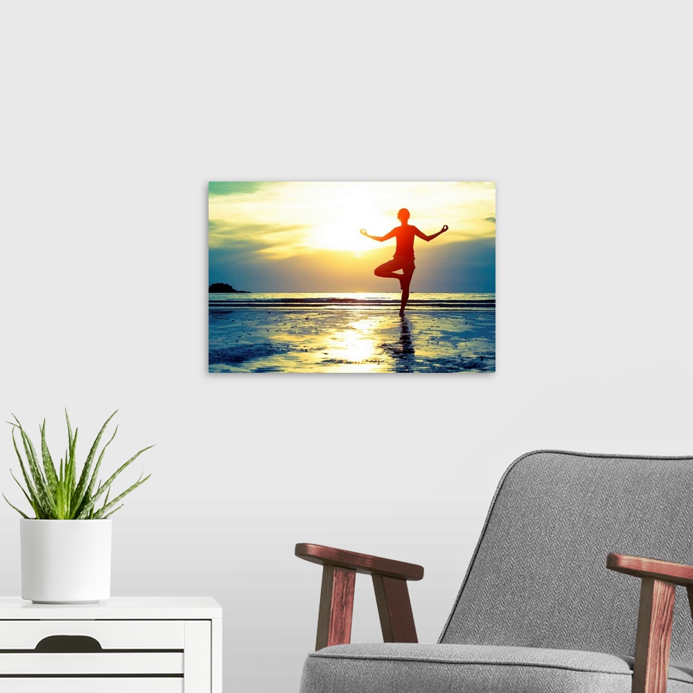 A modern room featuring Woman practicing yoga on the beach at sunset