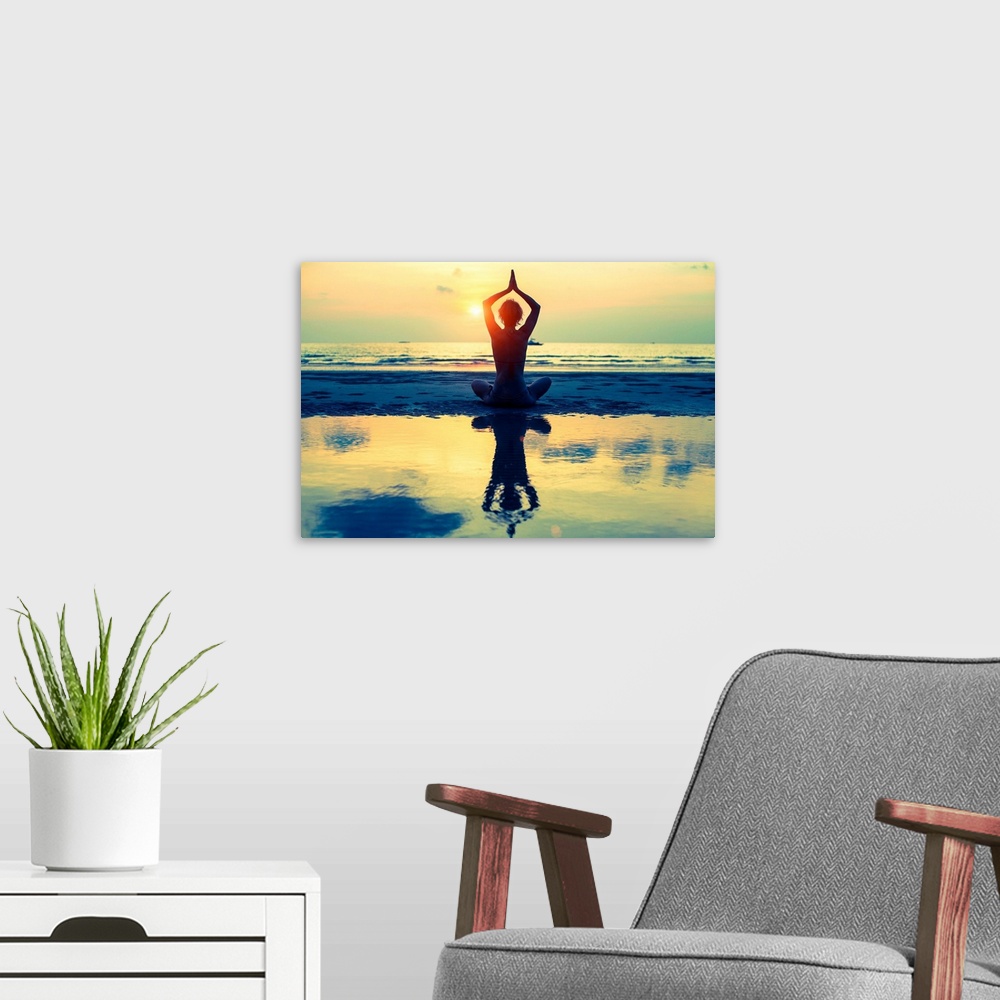 A modern room featuring Woman sitting in lotus pose on the beach during sunset