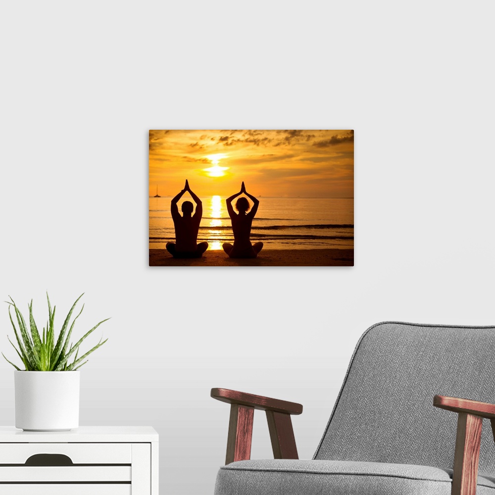 A modern room featuring Young couple practicing yoga on the sea beach at sunset