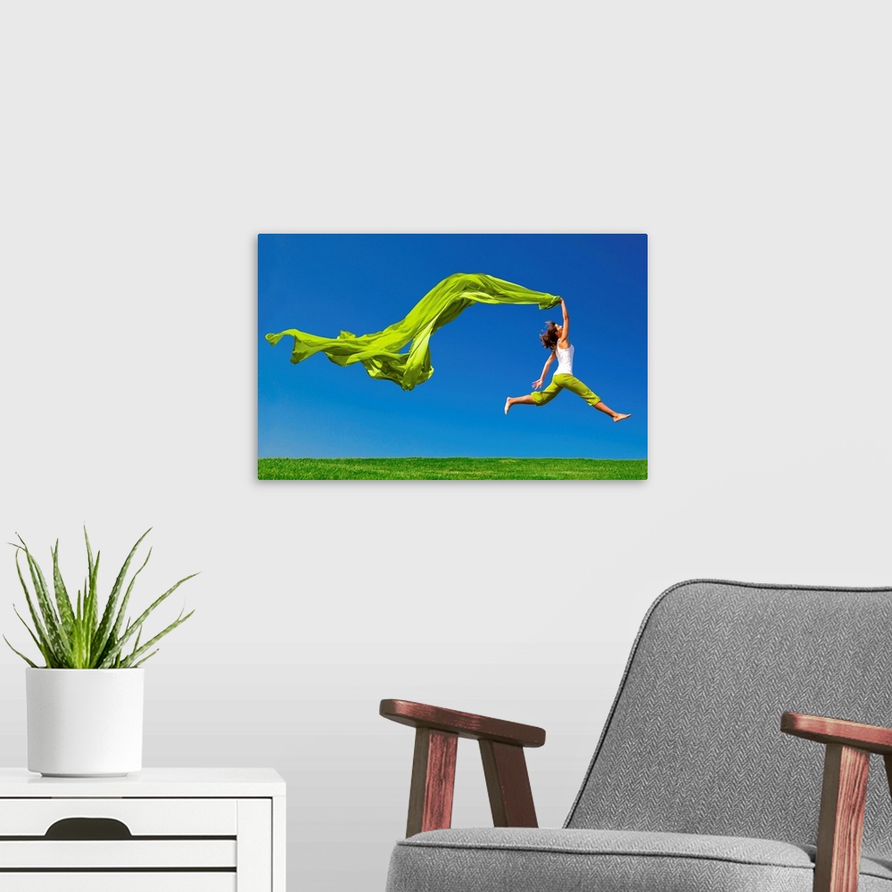 A modern room featuring Beautiful young woman jumping on  a green meadow with a colored tissue