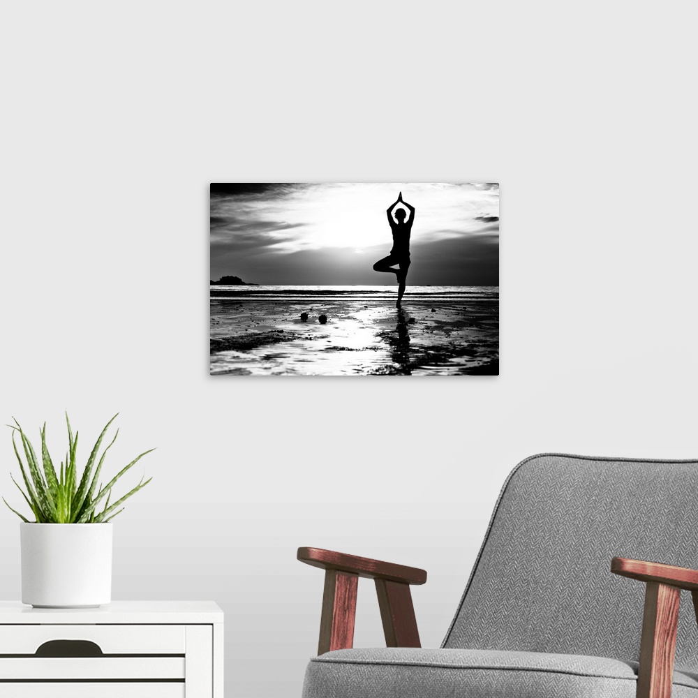 A modern room featuring Black and white picture: Young woman practicing yoga on the beach at sunset.