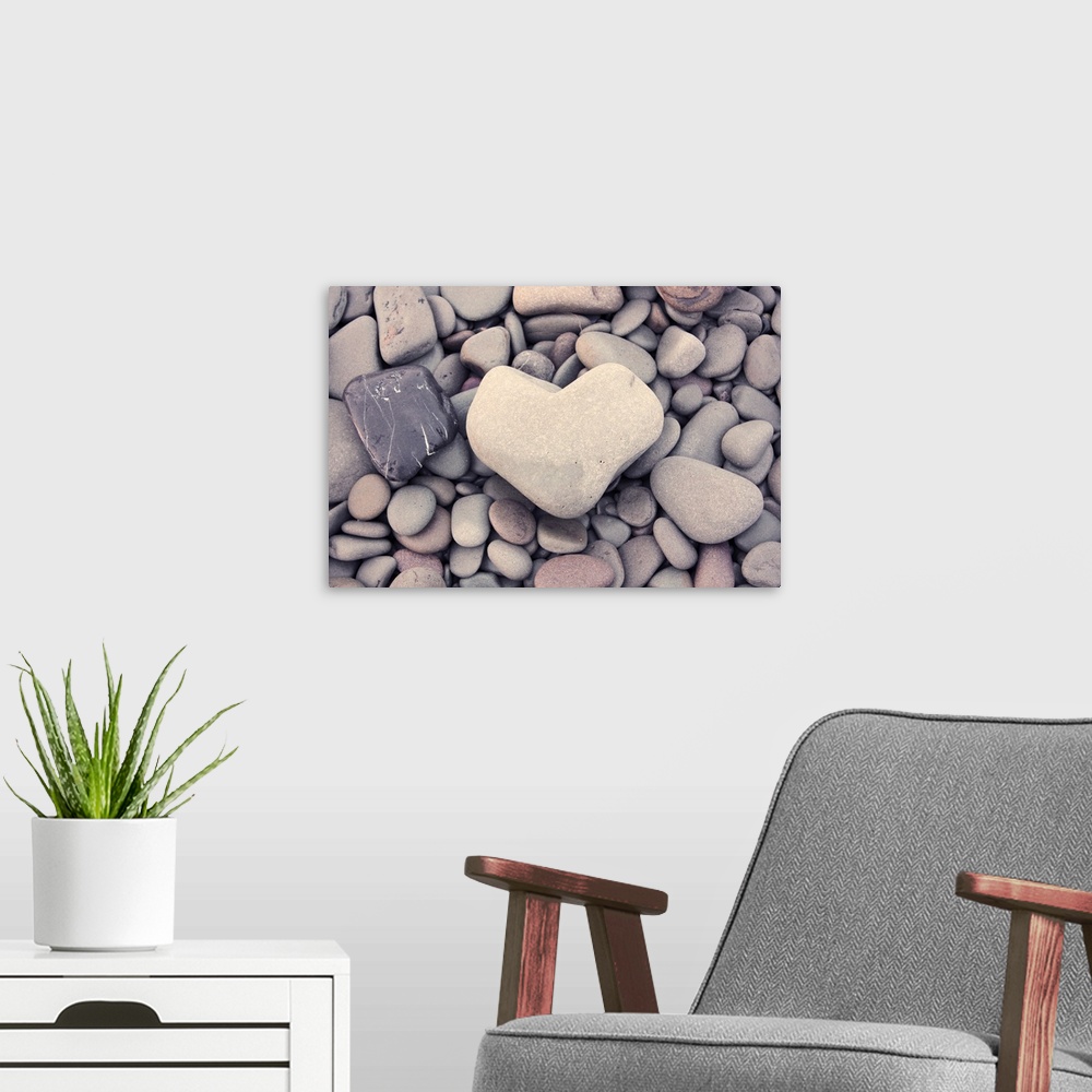 A modern room featuring A smooth stone in the shape of a heart on a bed of round pebbles.