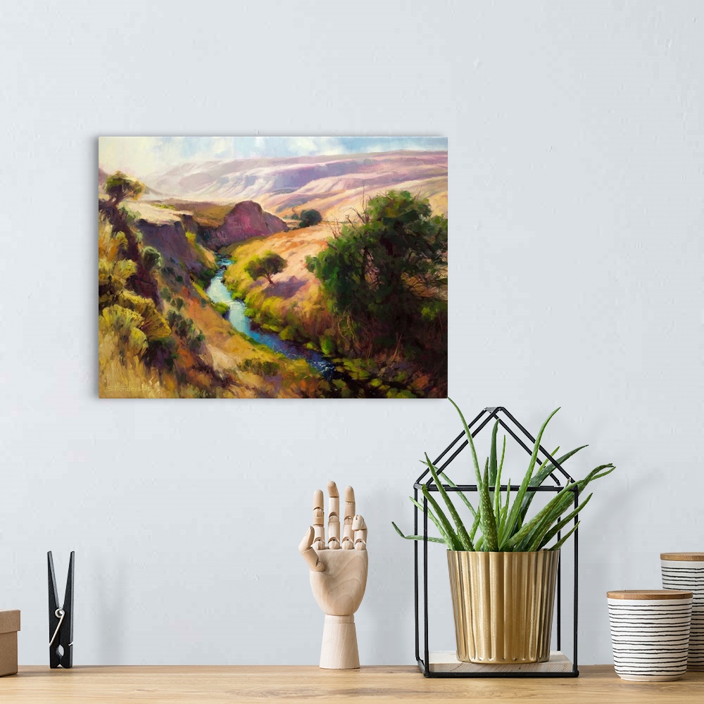A bohemian room featuring Traditional representational landscape painting of a shallow canyon with a river running through ...