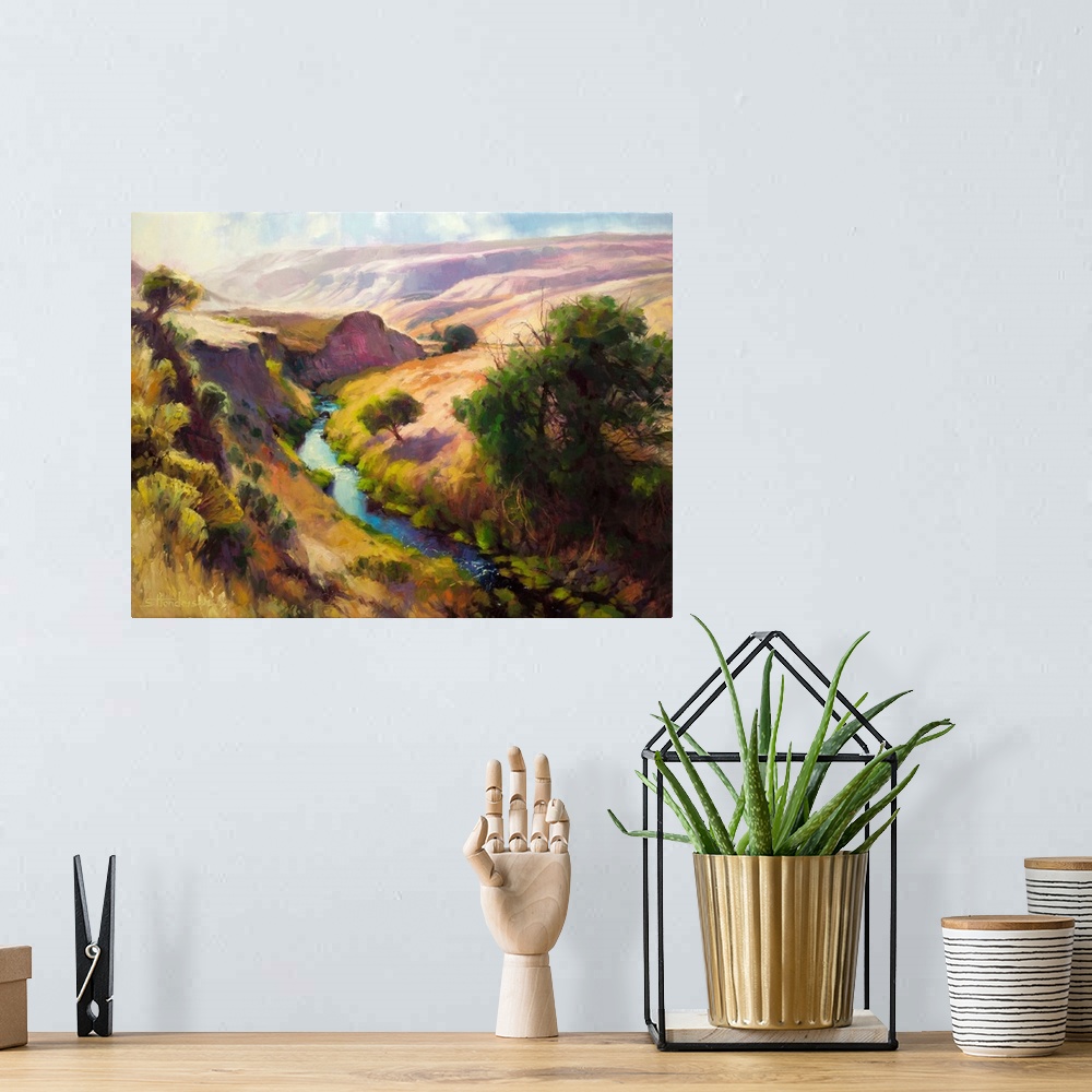 A bohemian room featuring Traditional representational landscape painting of a shallow canyon with a river running through ...
