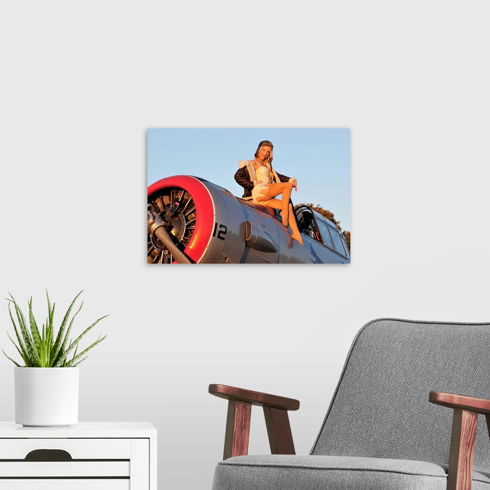 A modern room featuring 1940's style aviator pin-up girl posing with a vintage World War II T-6 Texan aircraft.