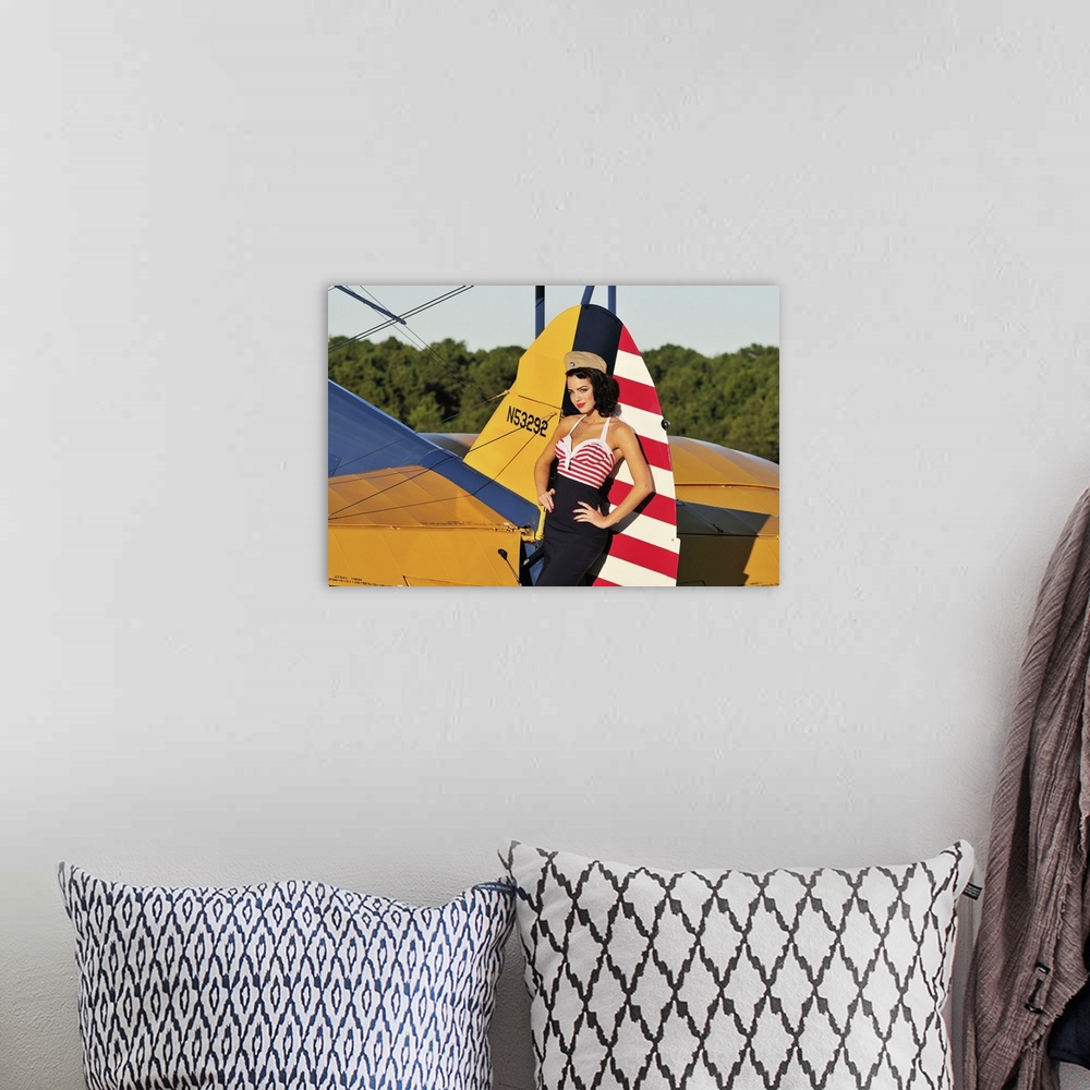 A bohemian room featuring Patriotic 1940's style pin-up girl leaning on the tail fin of a World War II Stearman biplane.
