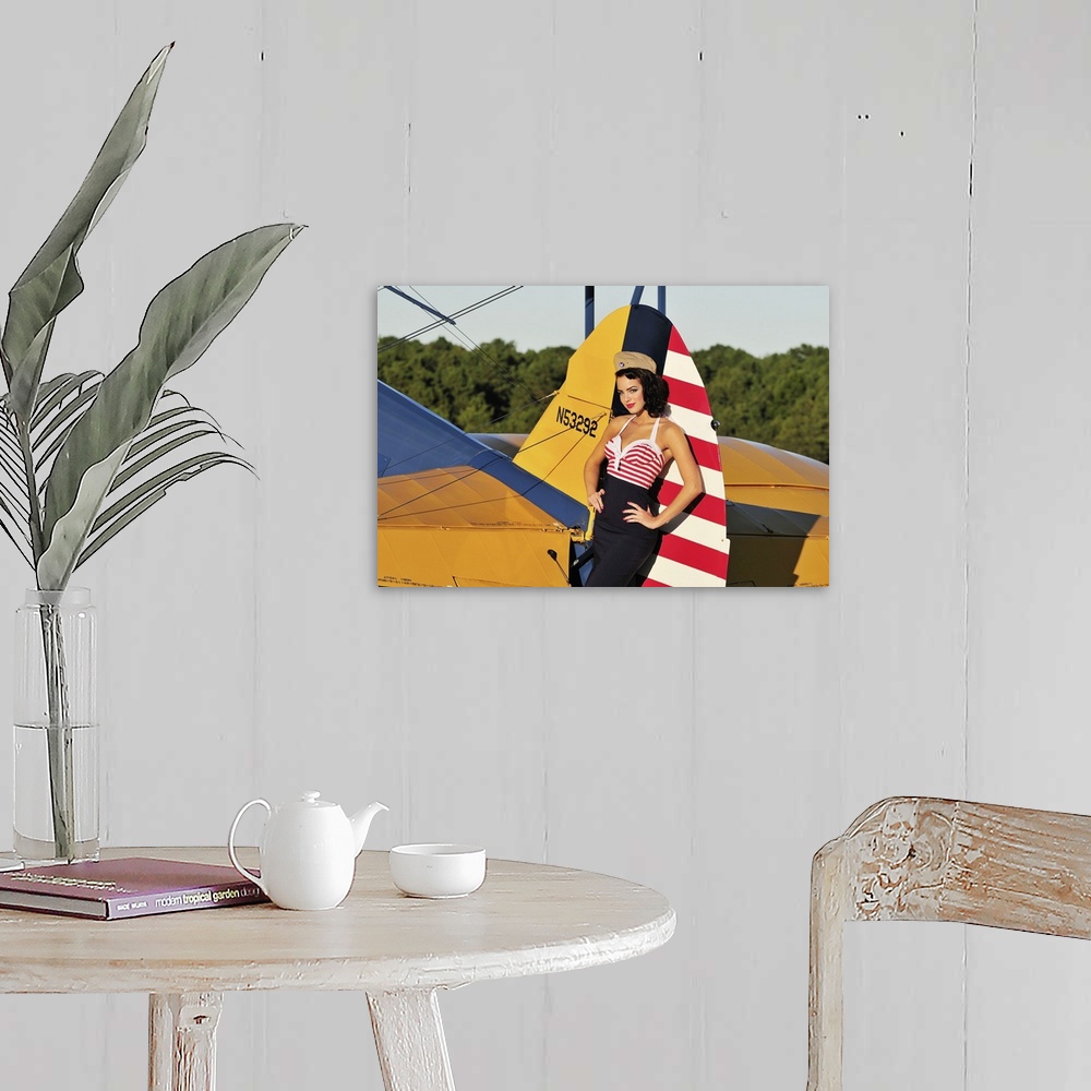 A farmhouse room featuring Patriotic 1940's style pin-up girl leaning on the tail fin of a World War II Stearman biplane.