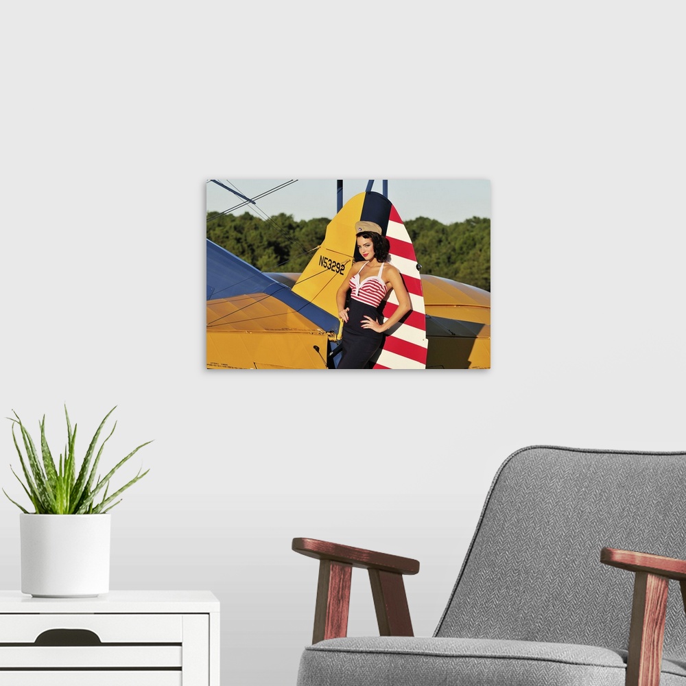 A modern room featuring Patriotic 1940's style pin-up girl leaning on the tail fin of a World War II Stearman biplane.