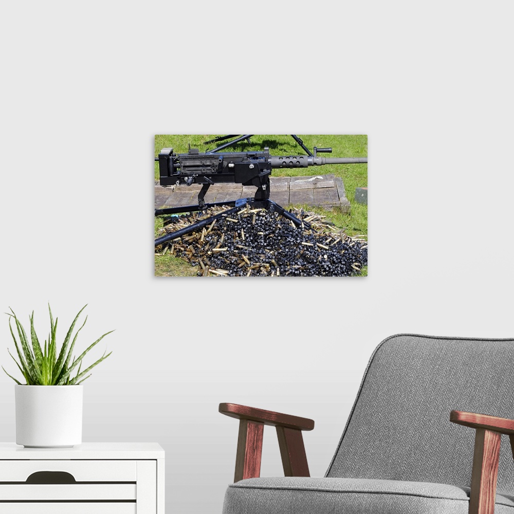 A modern room featuring Big, horizontal, close up photograph of a .50 caliber browning machine gun, sitting in the grass,...