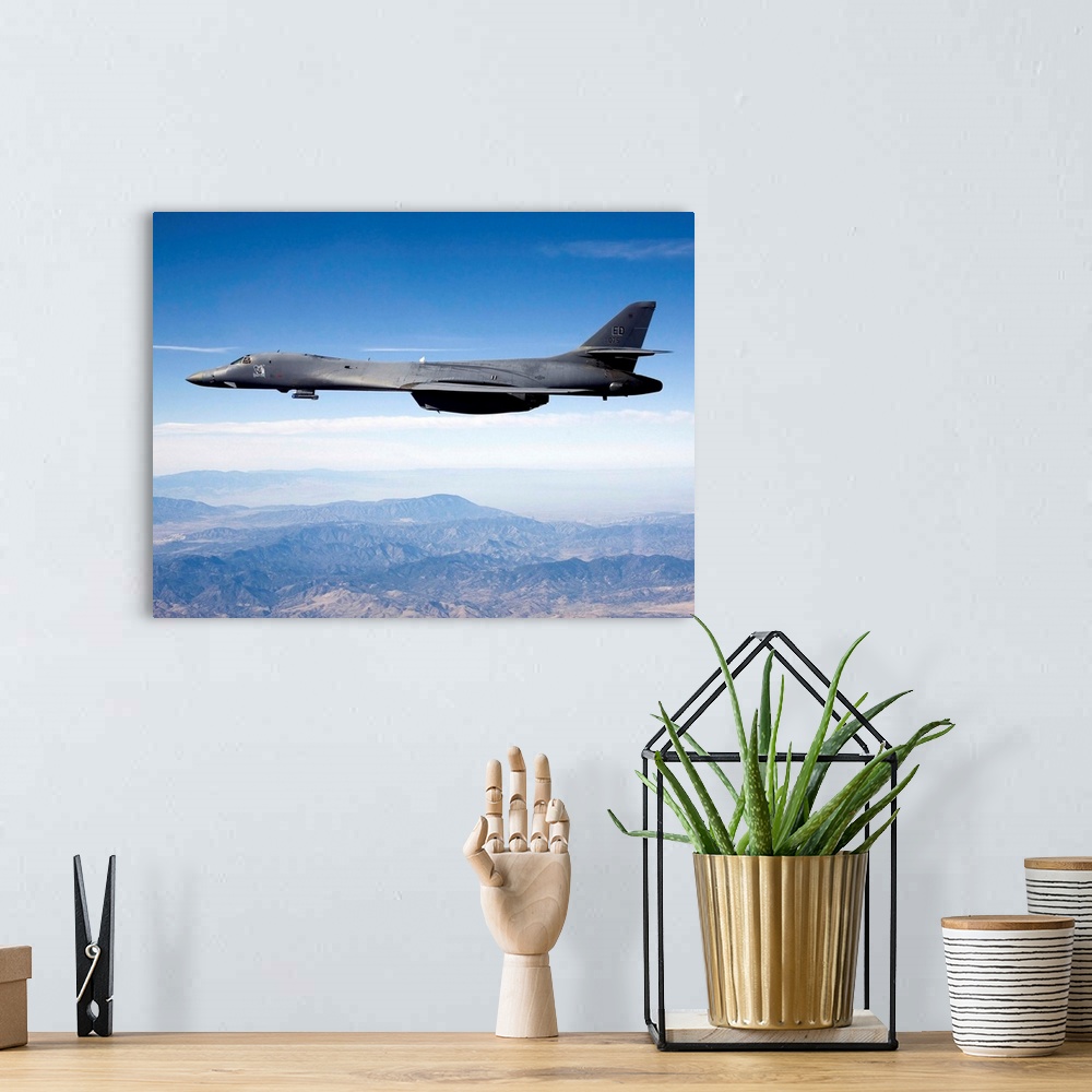 A bohemian room featuring A B-1B Lancer carries the Sniper pod on its belly as it flies through the sky.