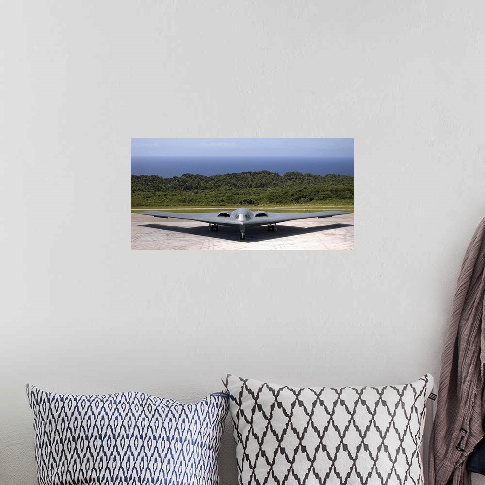 A bohemian room featuring A military aircraft is pictured while still on the terminal with the ocean just behind it.