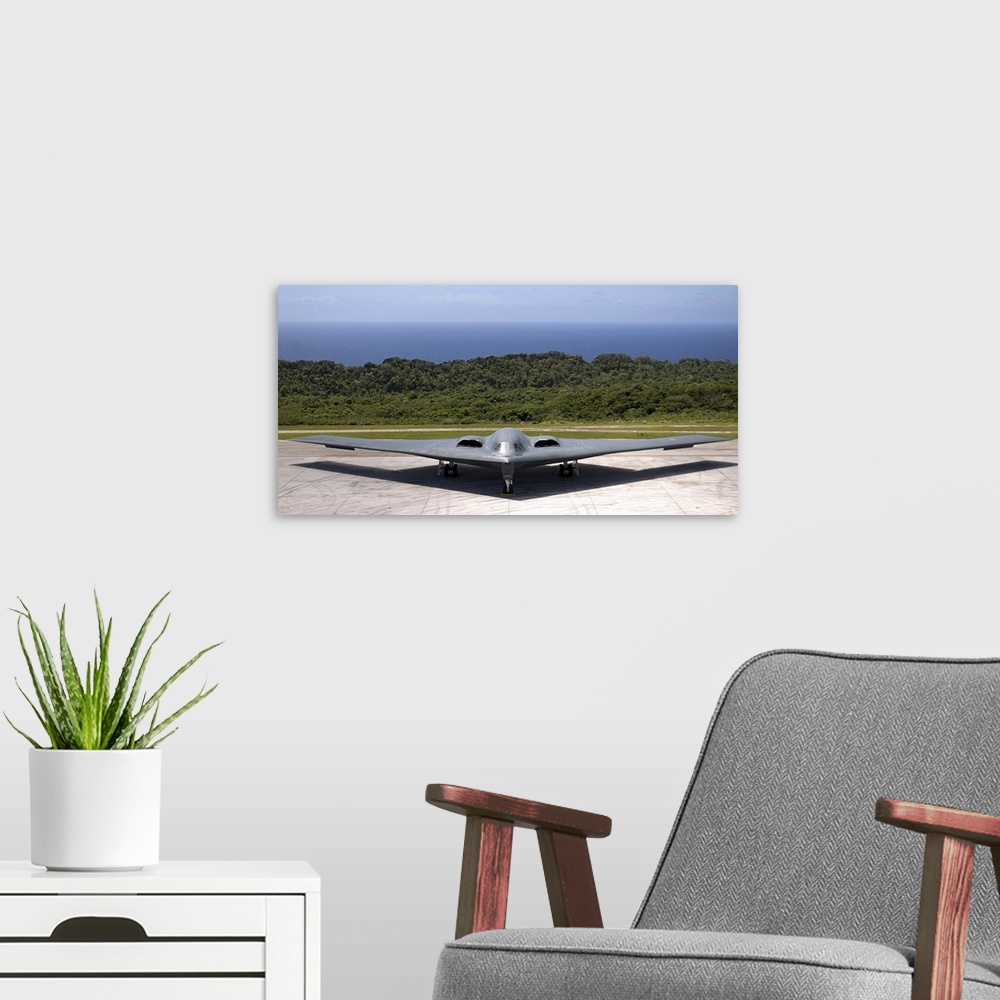 A modern room featuring A military aircraft is pictured while still on the terminal with the ocean just behind it.