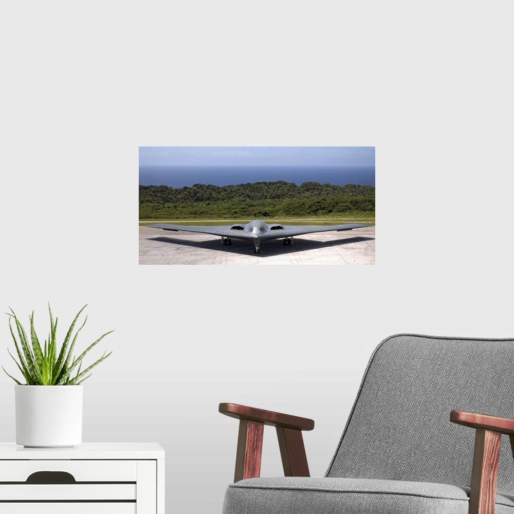 A modern room featuring A military aircraft is pictured while still on the terminal with the ocean just behind it.