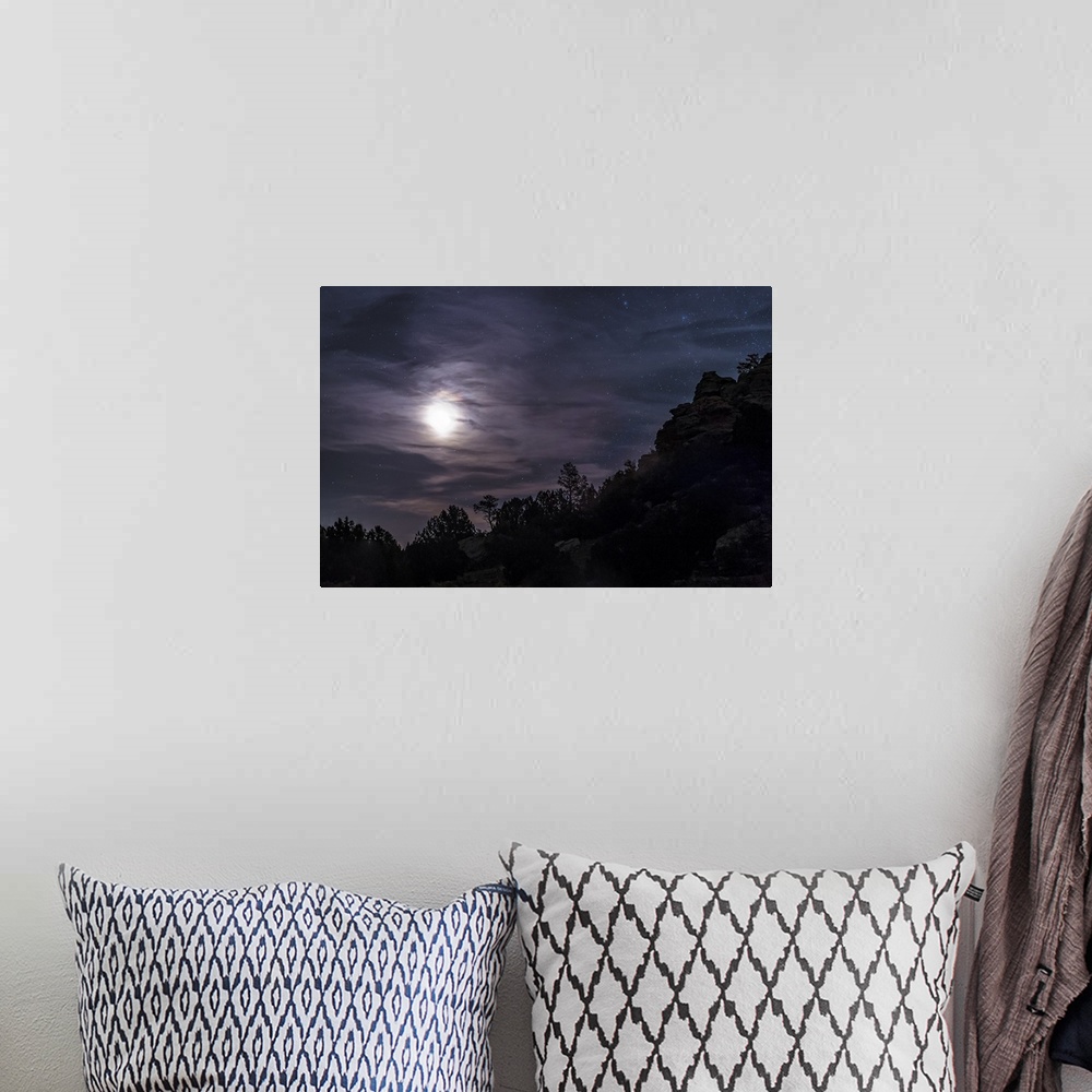 A bohemian room featuring A bright moon rises through clouds over a hill in Oklahoma, USA.