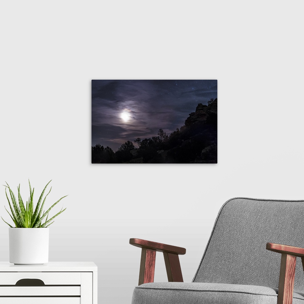 A modern room featuring A bright moon rises through clouds over a hill in Oklahoma, USA.