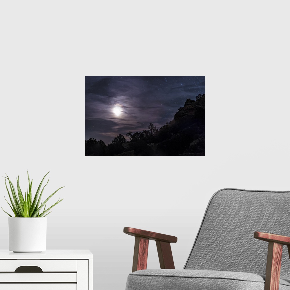 A modern room featuring A bright moon rises through clouds over a hill in Oklahoma, USA.