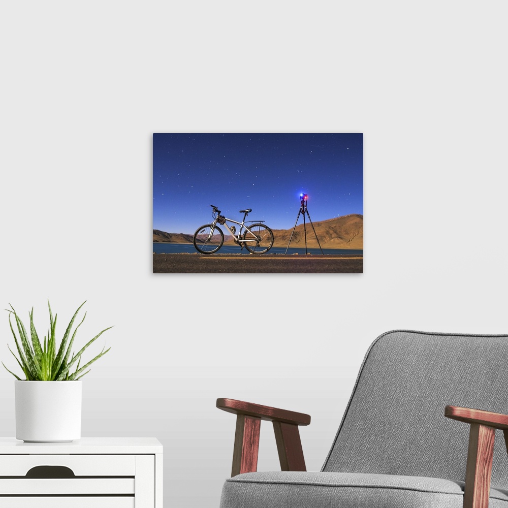 A modern room featuring Night adventure with a camera, tripod and bicycle at Yamdrok Lake, Tibet, China, in a full moon n...