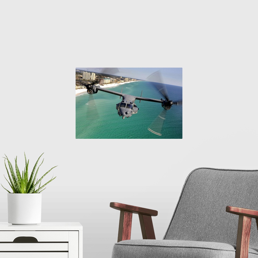 A modern room featuring Large landscape photograph of a CV22 Osprey aircraft flying toward the camera, over the green and...